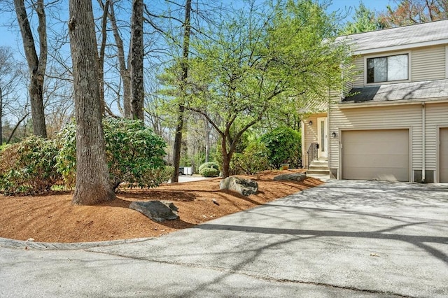 view of side of property with a garage, aphalt driveway, and a shingled roof