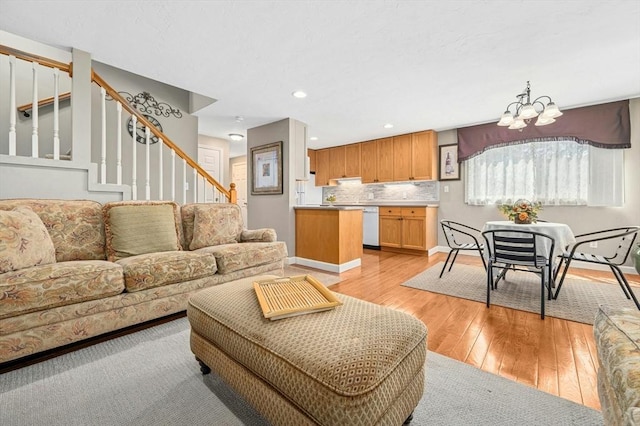 living room featuring baseboards, an inviting chandelier, stairway, and light wood-type flooring