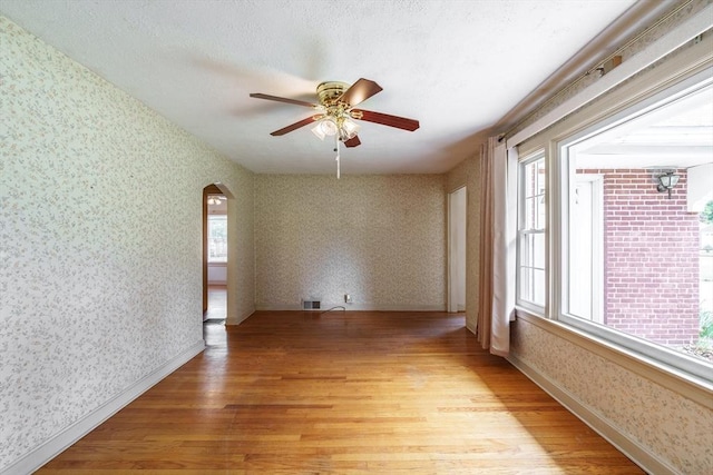 405 Granby Rd, South Hadley, MA 01075 - spare room with wallpapered walls, light wood-style floors, arched walkways, ceiling fan, and baseboards