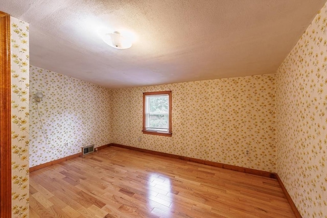 405 Granby Rd, South Hadley, MA 01075 - additional living space featuring light wood finished floors, a textured ceiling, wallpapered walls, and baseboards