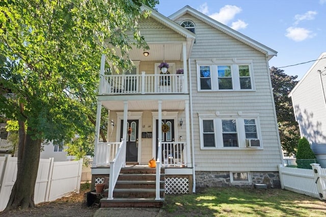 view of front of property featuring a porch, a front lawn, a balcony, and fence