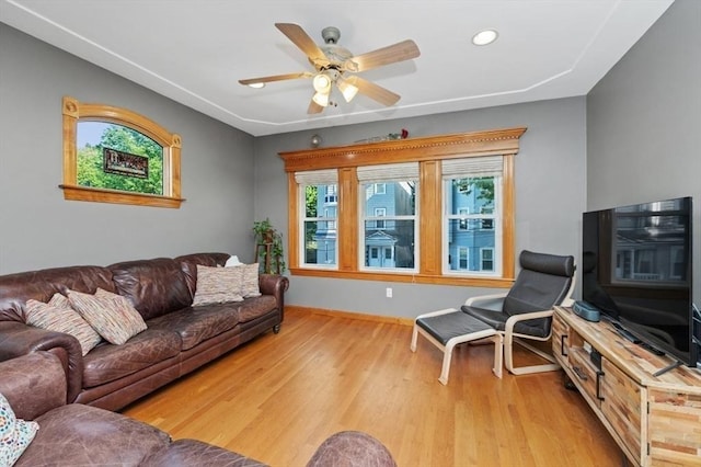 living area with baseboards, a ceiling fan, and wood finished floors