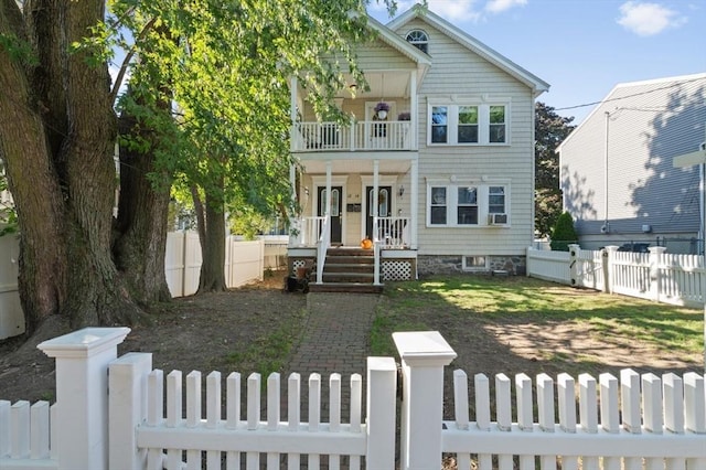 view of front facade featuring a fenced front yard, covered porch, cooling unit, and a balcony