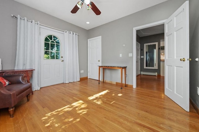 foyer entrance with ceiling fan, light wood-style floors, baseboards, and a baseboard radiator