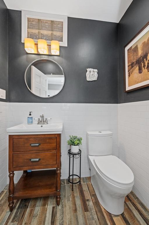 bathroom featuring a wainscoted wall, toilet, vanity, and wood finished floors