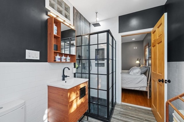 ensuite bathroom with vanity, tile walls, wood finished floors, and a shower stall