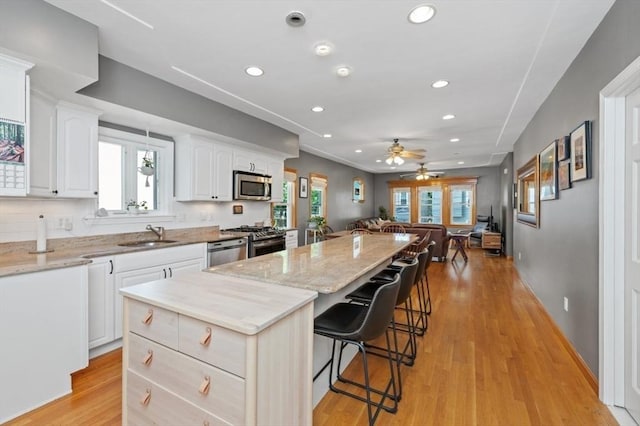 kitchen featuring stainless steel appliances, a kitchen bar, a center island, and light stone countertops