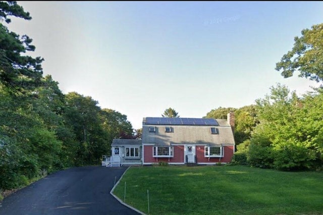34 Charles Rd, Harwich, MA 02645 - view of front facade with driveway, a chimney, a front yard, solar panels, and a gambrel roof