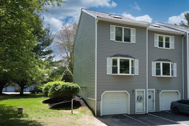 view of home's exterior with an attached garage, driveway, a lawn, and a shingled roof