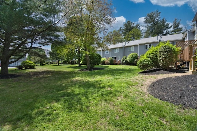 view of grassy yard with stairway and a wooden deck