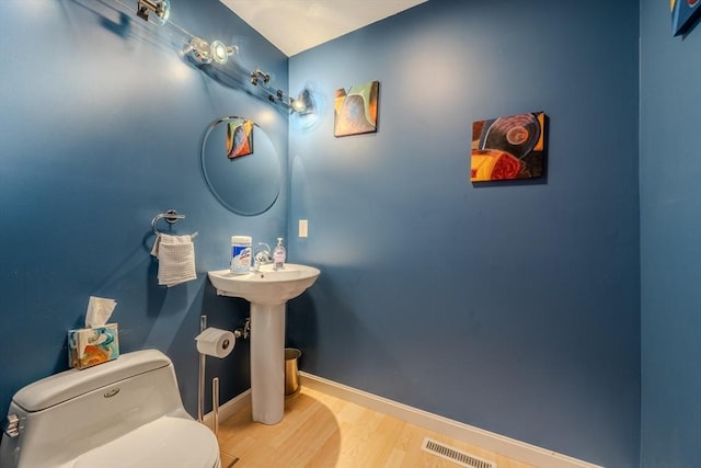 bathroom with wood finished floors, toilet, and baseboards