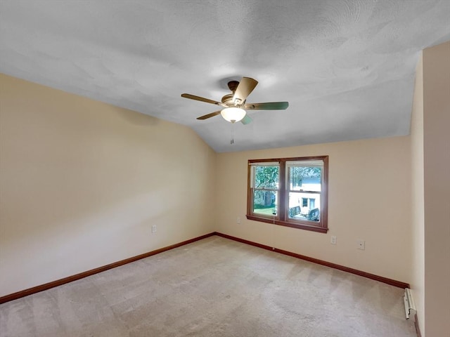 empty room with vaulted ceiling, light colored carpet, ceiling fan, and baseboard heating