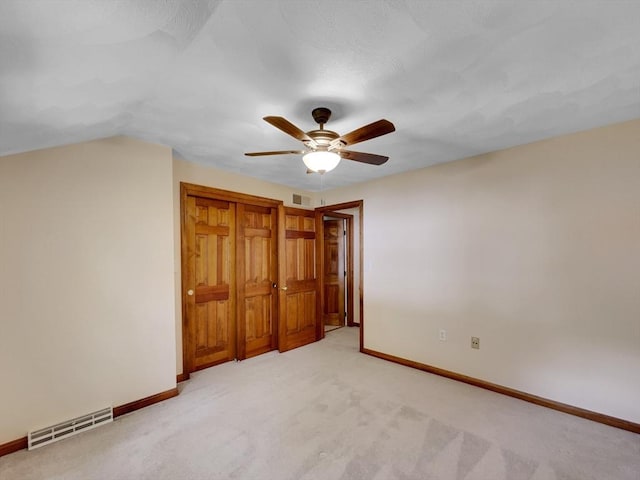 unfurnished bedroom featuring vaulted ceiling, light carpet, ceiling fan, and a closet