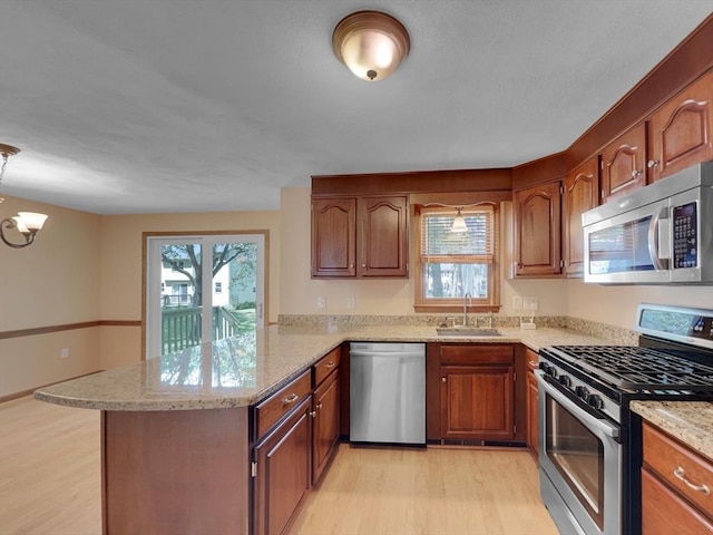 kitchen featuring light hardwood / wood-style floors, appliances with stainless steel finishes, kitchen peninsula, and sink