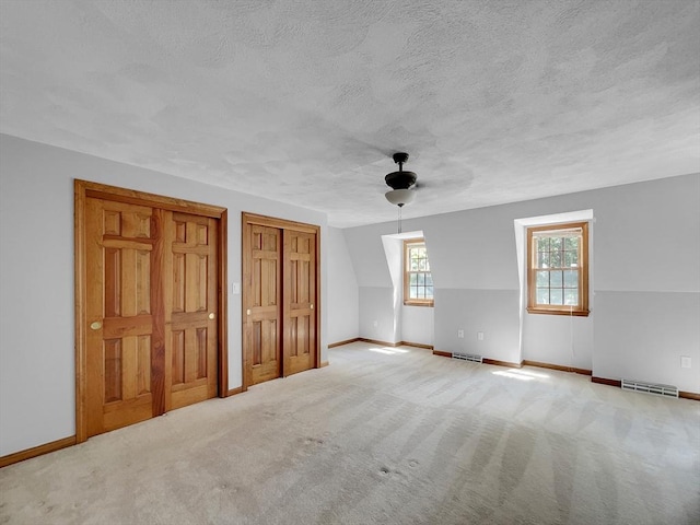 bonus room with ceiling fan, vaulted ceiling, light colored carpet, and a textured ceiling