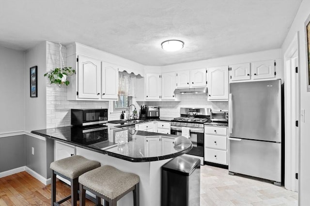 119 Wellman Ave Unit 119, Chelmsford, MA 01863 - kitchen with stainless steel appliances, under cabinet range hood, a peninsula, decorative backsplash, and white cabinetry