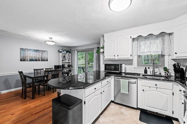 119 Wellman Ave Unit 119, Chelmsford, MA 01863 - kitchen with appliances with stainless steel finishes, a peninsula, a sink, white cabinets, and tasteful backsplash