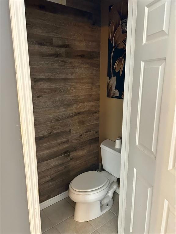 bathroom with toilet, wood walls, and tile patterned flooring