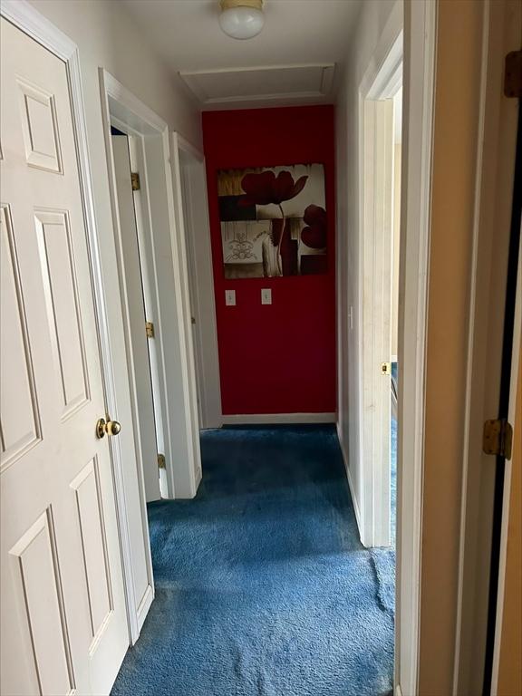 hall featuring dark colored carpet