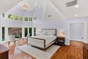 bedroom featuring a towering ceiling, wood finished floors, and baseboards