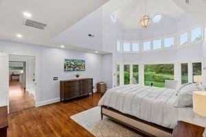 bedroom featuring a towering ceiling, recessed lighting, wood finished floors, a chandelier, and french doors
