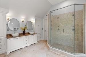 full bath with lofted ceiling, a stall shower, and double vanity