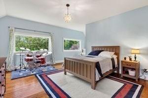 bedroom featuring wood finished floors, multiple windows, lofted ceiling, and a chandelier