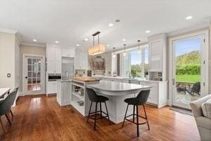 kitchen featuring open shelves, a breakfast bar area, white cabinetry, ornamental molding, and light countertops