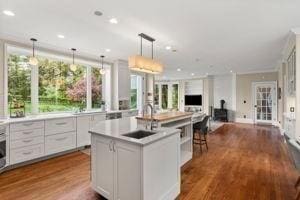 kitchen featuring a wood stove, a kitchen island with sink, light countertops, open floor plan, and dark wood-style flooring