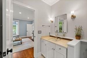 bathroom featuring ornamental molding, plenty of natural light, vanity, and wood finished floors