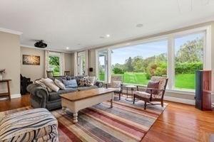 living area with wood finished floors, baseboards, and crown molding