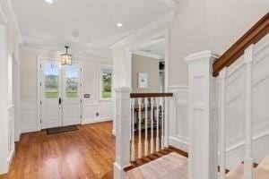 foyer entrance featuring a decorative wall, ornamental molding, wood finished floors, a wainscoted wall, and recessed lighting