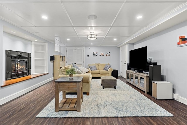 living area with recessed lighting, wood finished floors, baseboards, and a glass covered fireplace