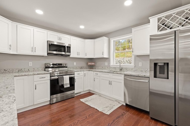 kitchen featuring light stone countertops, dark wood-type flooring, white cabinetry, a sink, and stainless steel appliances