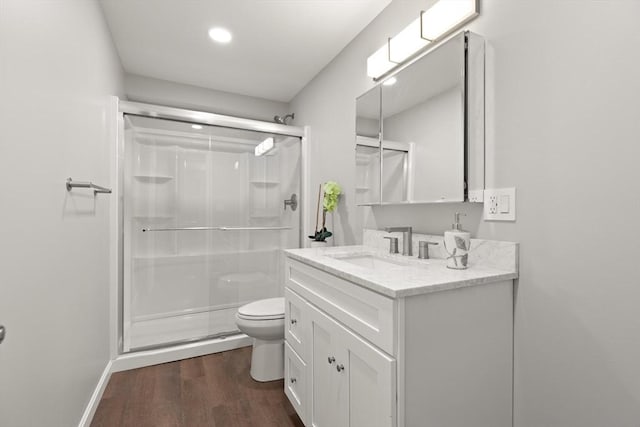 full bath featuring a stall shower, wood finished floors, vanity, toilet, and recessed lighting