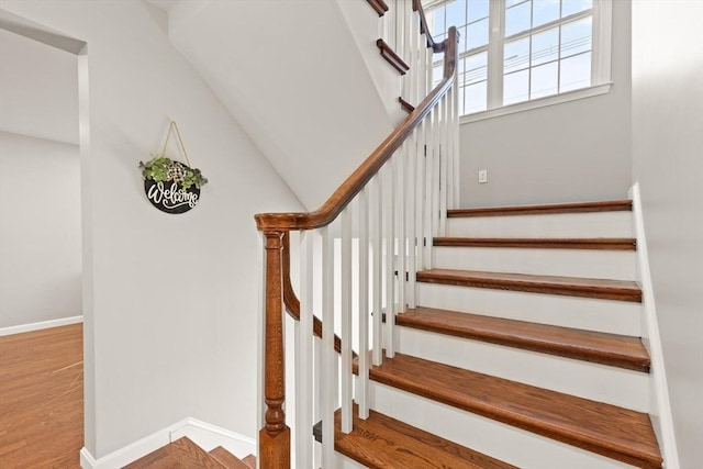 staircase featuring baseboards and wood finished floors