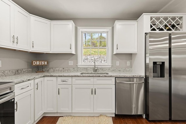 kitchen with a sink, white cabinetry, appliances with stainless steel finishes, and light stone countertops