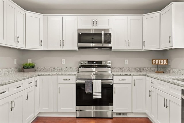 kitchen featuring white cabinetry, appliances with stainless steel finishes, light stone counters, and visible vents