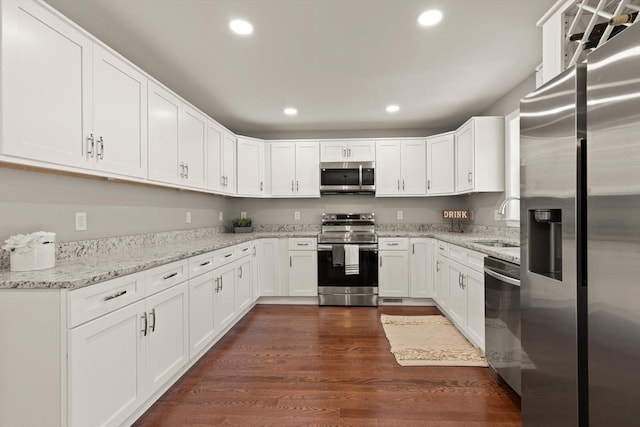 kitchen featuring a sink, stainless steel appliances, recessed lighting, white cabinetry, and dark wood-type flooring