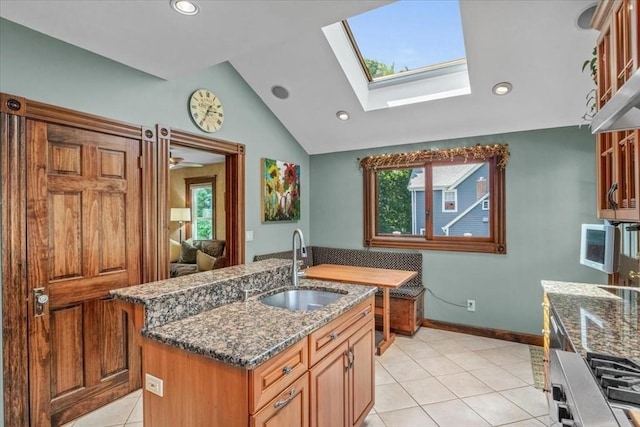 100 Williams Ave, Boston, MA 02136 - kitchen featuring a skylight, vaulted ceiling, a center island with sink, dark stone countertops, and light tile patterned flooring
