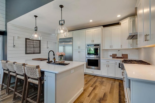 kitchen featuring pendant lighting, recessed lighting, light countertops, light wood-style flooring, and appliances with stainless steel finishes