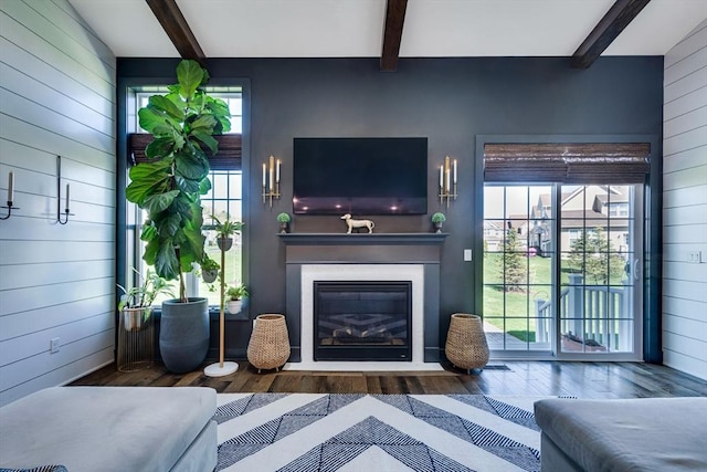 living room with wood finished floors, wooden walls, and beamed ceiling