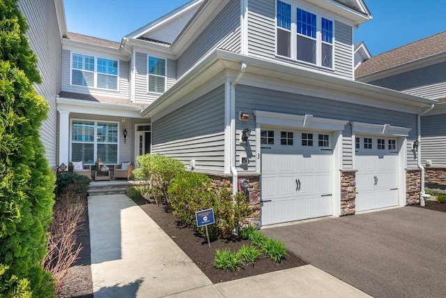 view of front of house featuring an attached garage, driveway, and stone siding