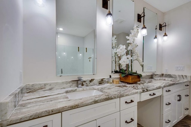 bathroom featuring double vanity, a sink, and a shower with shower door