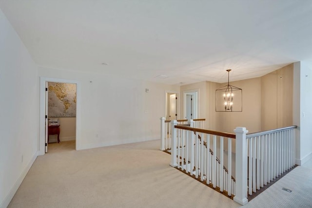 hallway featuring baseboards, an upstairs landing, light carpet, and an inviting chandelier