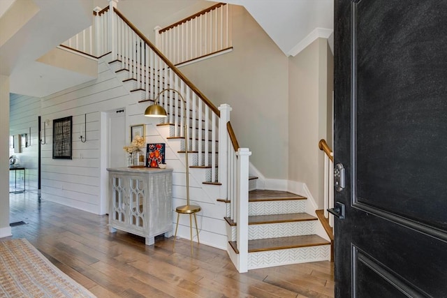 staircase with wooden walls, baseboards, ornamental molding, and hardwood / wood-style flooring