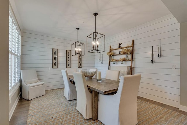 dining room featuring wooden walls, a notable chandelier, plenty of natural light, and light wood-type flooring