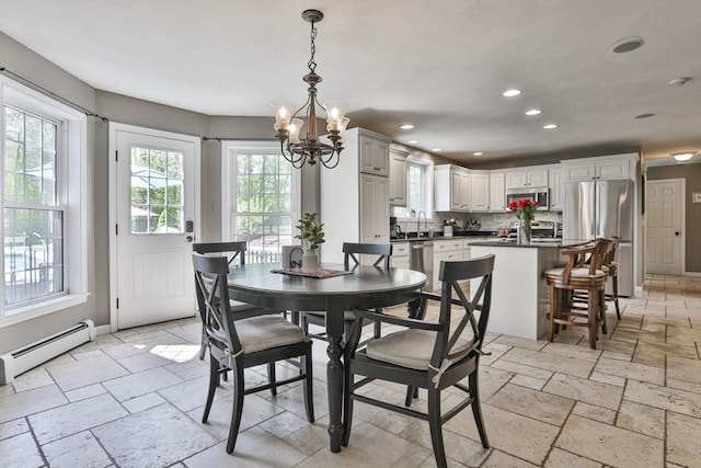 dining space featuring a chandelier, stone tile flooring, recessed lighting, a baseboard heating unit, and baseboards