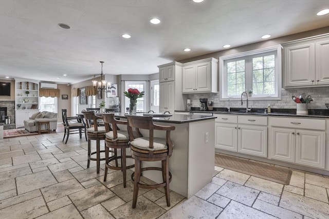 kitchen featuring a sink, recessed lighting, stone tile flooring, plenty of natural light, and backsplash
