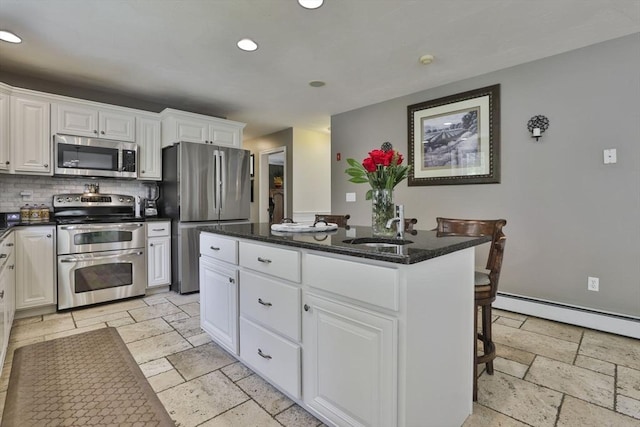 kitchen with appliances with stainless steel finishes, stone tile floors, a sink, a center island, and recessed lighting